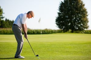 Älterer Mann beim Golfabschlag
